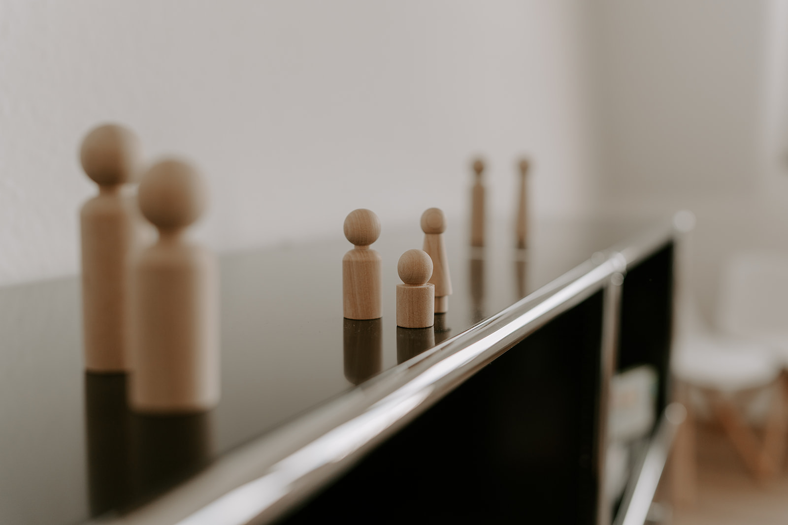 Auf einem schwarzen Sideboard stehen hölzerne Familienaufstellungsfiguren